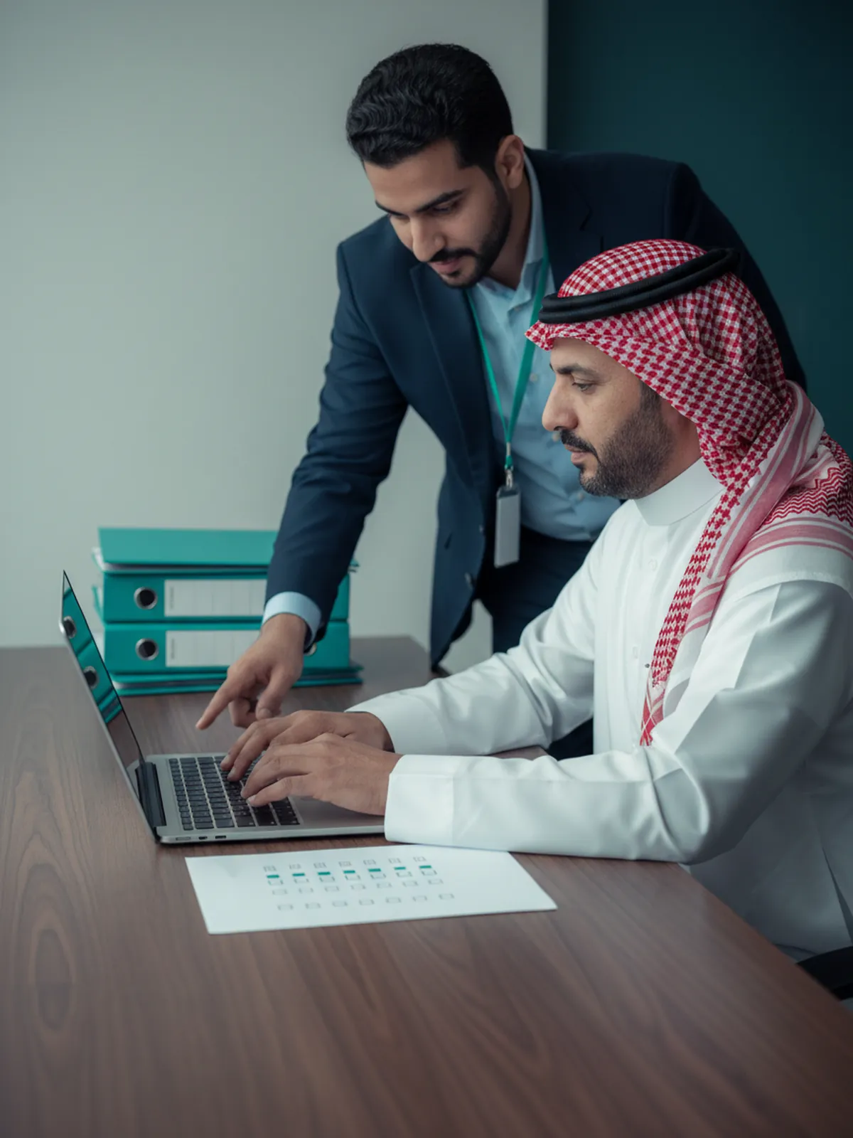 The general manager of a contracting company submits the application from his company's account, with an Edaaat consultant beside him following the checklist
